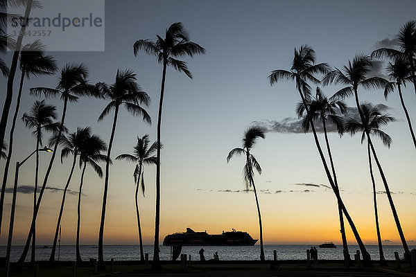 Silhouette eines Kreuzfahrtschiffs auf dem Wasser vor dem Ufer der Kailua Bay bei Sonnenuntergang; Kailua-Kona  Insel Hawaii  Hawaii  Vereinigte Staaten von Amerika