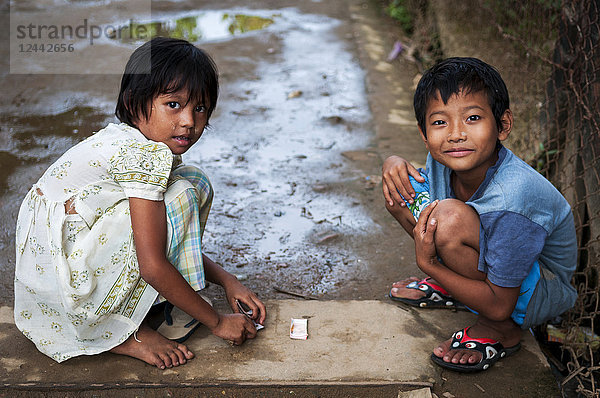 Zwei kleine Kinder spielen Karten in einer der Seitenstraßen von Yangon; Yangon  Myanmar