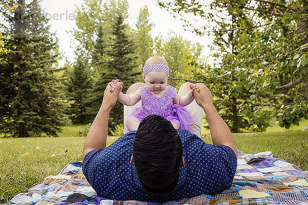 Ein Vater spielt mit seiner kleinen Tochter  während er auf einer Decke in einem Stadtpark im Spätsommer liegt; Edmonton  Alberta  Kanada