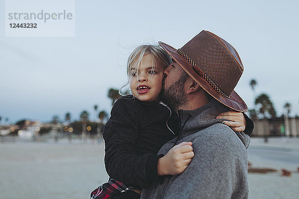 Ein Vater und seine Tochter haben einen zärtlichen Moment  der Vater hält seine Tochter in einer Umarmung an einem Strand in der Abenddämmerung; Long Beach  Kalifornien  Vereinigte Staaten von Amerika