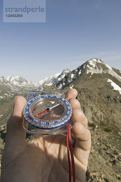 Wanderer's Hand hält einen Kompass  zeigt in Richtung der Berge  Chugach Mountains  Southcentral  Alaska  Sommer