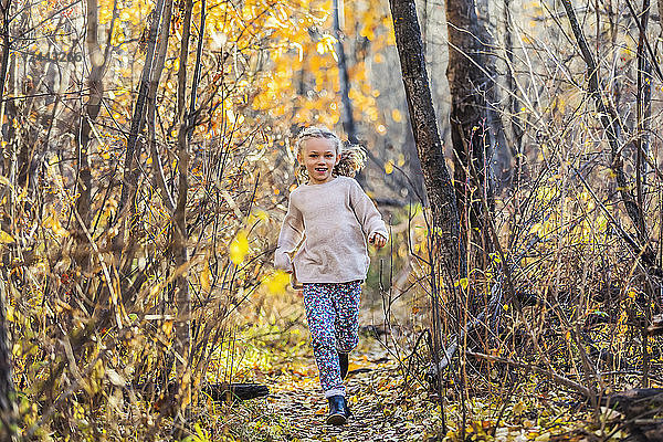 Ein junges Mädchen läuft an einem warmen Herbstabend durch den Wald in einem Stadtpark; Edmonton  Alberta  Kanada