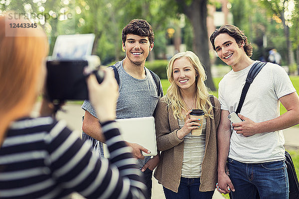 Eine junge Frau fotografiert drei Freunde auf dem Universitätscampus  Edmonton  Alberta  Kanada