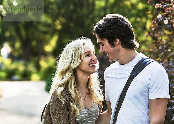 Ein junges Paar genießt einen romantischen Moment und denkt über einen Kuss nach  während es durch einen Universitätscampus geht  Edmonton  Alberta  Kanada