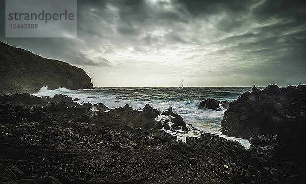 Zerklüftete Landschaft entlang der Atlantikküste mit einer Jacht im Sturm  Insel Sao Miguel  Azoren  Portugal