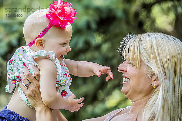 Eine schöne junge Mutter mit langen blonden Haaren genießt die Zeit mit ihrer süßen kleinen Tochter in einem Stadtpark an einem Sommertag  Edmonton  Alberta  Kanada