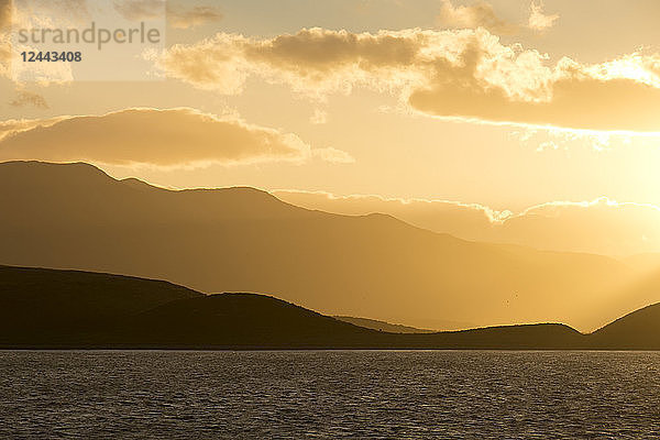 Goldener Sonnenuntergang vom Meer aus gesehen mit den Küstenbergen als Silhouette; Ushuaia  Feuerland  Argentinien