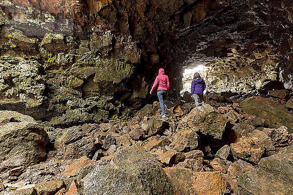Zwei Touristinnen beim Wandern durch die Lavaröhrenhöhlen  Island