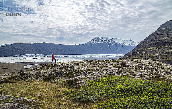 Eine Wanderin wandert am Rande eines Hügels auf dem Weg oberhalb eines Gletschersees und eines Aussichtspunkts in Südisland  Vatnajokull-Nationalpark  Island
