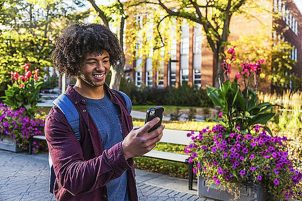 Ein junger afroamerikanischer Student benutzt sein Smartphone auf einem Universitätscampus in Edmonton  Alberta  Kanada