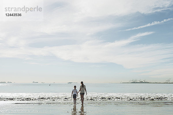Zwei Schwestern  die an einem Strand zur Brandung hinausgehen; Long Beach  Kalifornien  Vereinigte Staaten von Amerika