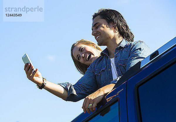 Ein junges Paar steht durch das Schiebedach seines Autos auf und macht ein Selbstporträt mit seinem Handy  Edmonton  Alberta  Kanada