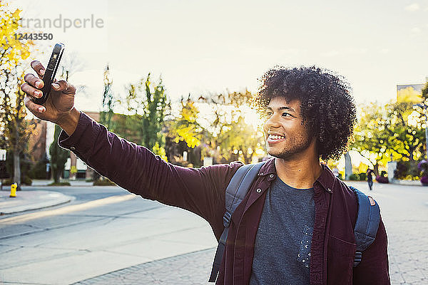 Ein junger afroamerikanischer Universitätsstudent posiert für ein Selbstporträt mit seinem Smartphone  Edmonton  Alberta  Kanada