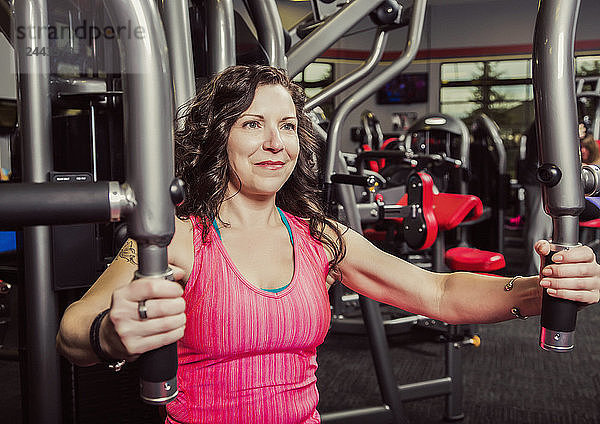 Eine Frau mittleren Alters trainiert in einer Fitnesseinrichtung mit einer Brustfliege  Spruce Grove  Alberta  Kanada