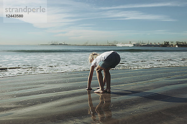 Ein junges Mädchen spielt im nassen Sand an der Küste; Long Beach  Kalifornien  Vereinigte Staaten von Amerika