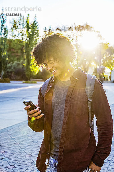 Ein junger afroamerikanischer Student benutzt sein Smartphone auf einem Universitätscampus in Edmonton  Alberta  Kanada