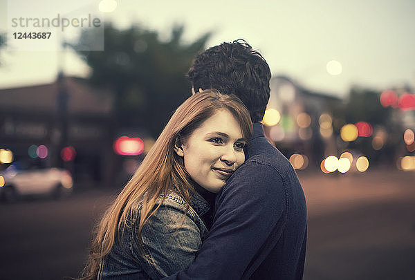 Ein junges Paar umarmt sich in der Abenddämmerung auf einem Bürgersteig in einer beliebten Gegend  Edmonton  Alberta  Kanada
