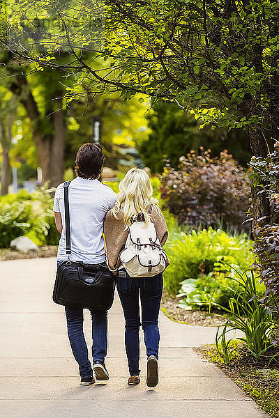 Ein junges Paar geht händchenhaltend einen Weg auf dem Universitätscampus entlang  Edmonton  Alberta  Kanada