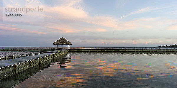 Eine Bank auf einem Steg mit Blick auf die Küste und den offenen Ozean bei Sonnenaufgang  Belize