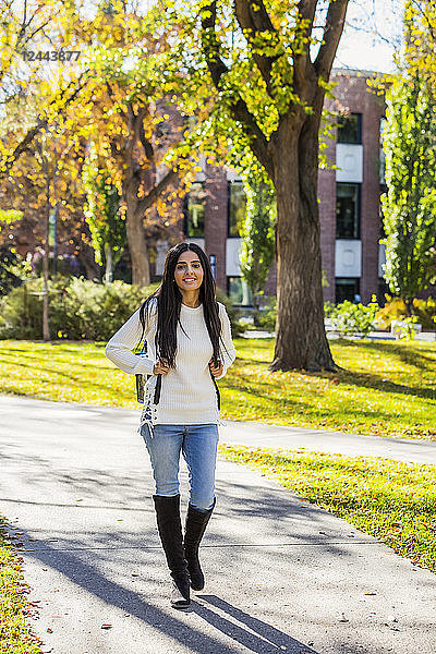 Eine junge Studentin libanesischer Abstammung geht mit einem Rucksack auf einem Weg auf dem Campus  Edmonton  Alberta  Kanada