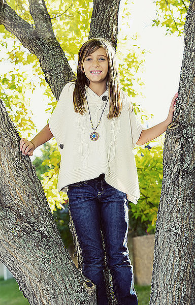 Porträt eines jungen Mädchens  das in einem Baum in einem Park im Herbst steht  Edmonton  Alberta  Kanada