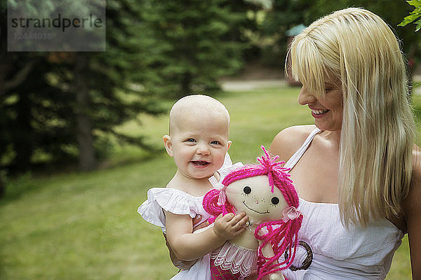 Eine hübsche junge Mutter geht mit ihrer kleinen Tochter spazieren und genießt die gemeinsame Zeit in einem Park an einem warmen Sommertag  Edmonton  Alberta  Kanada