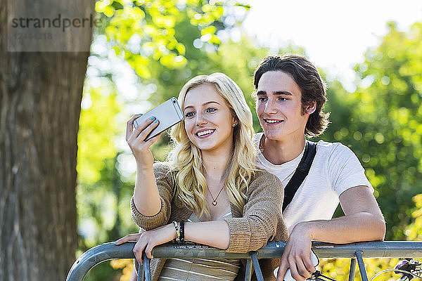 Ein junges Paar steht zusammen an einem Fahrradständer auf dem Universitätscampus und macht ein Selbstporträt mit einem Smartphone  Edmonton  Alberta  Kanada