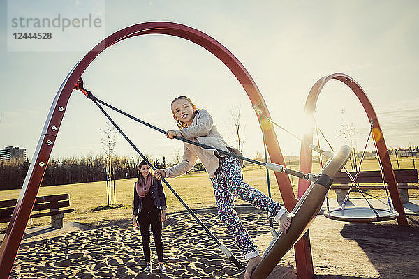 Eine junge Mutter und ihre Tochter spielen auf einer Untertassenschaukel auf einem Spielplatz an einem warmen Herbstabend; Edmonton  Alberta  Kanada