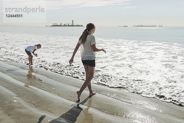 Zwei Schwestern  die an einem Strand zur Brandung hinausgehen; Long Beach  Kalifornien  Vereinigte Staaten von Amerika