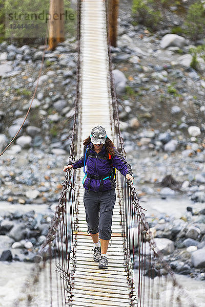 Wanderin überquert eine hölzerne Fußgängerbrücke auf dem Weg zum Gulkana-Gletscher  Alaska  Vereinigte Staaten von Amerika