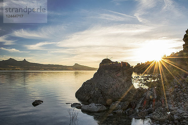 Die Sonne geht über einem See auf und verursacht einen Sonnenstich auf der rechten Seite des Bildes; Neuquen  Argentinien