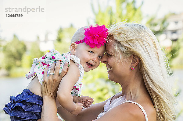 AA schöne junge Mutter mit langen blonden Haaren genießt die Zeit mit ihrer süßen kleinen Tochter in einem Stadtpark an einem Sommertag  Edmonton  Alberta  Kanada