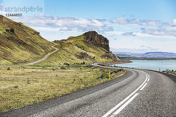 Eine lange  kurvenreiche Straße  die in die Berge Islands führt  wo offene  gepflasterte Straßen durch die vulkanische Landschaft zu Ausblicken über das Land führen  Island