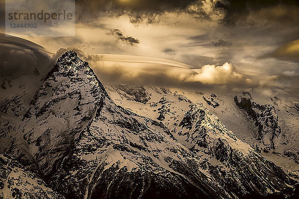 Dramatischer Blick auf das schneebedeckte Kaukasusgebirge und leuchtende Wolken  Region Dombay  Republik Karatschajewo-Tscherkesskaja  Russland