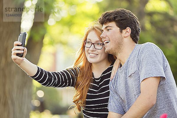 Ein junger Mann und eine junge Frau machen ein Selbstporträt mit einem Smartphone  Edmonton  Alberta  Kanada