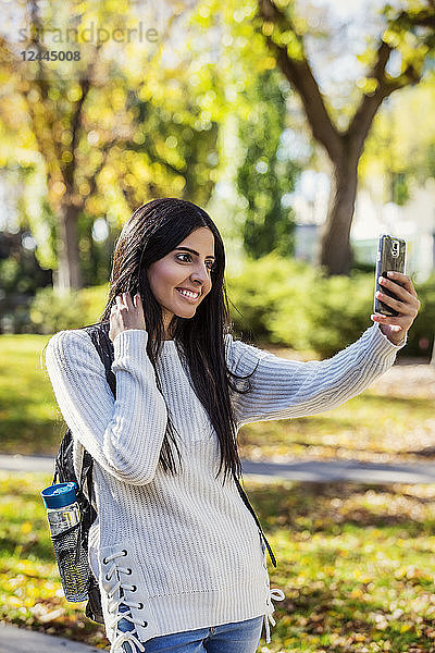 Eine junge Universitätsstudentin libanesischer Abstammung posiert für ein Selbstporträt mit ihrem Smartphone  Edmonton  Alberta  Kanada