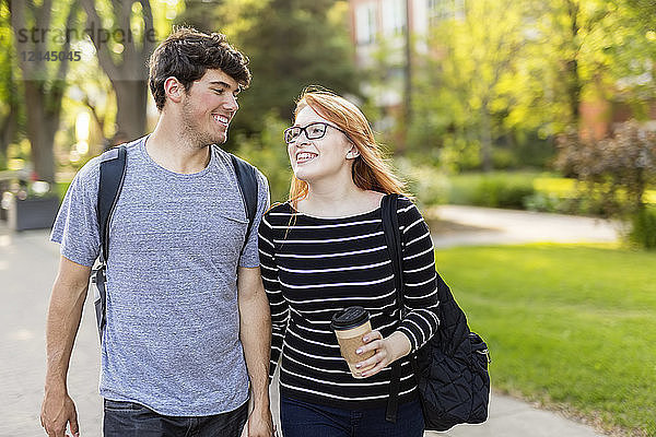 Ein junges Paar geht händchenhaltend durch einen Universitätscampus  Edmonton  Alberta  Kanada