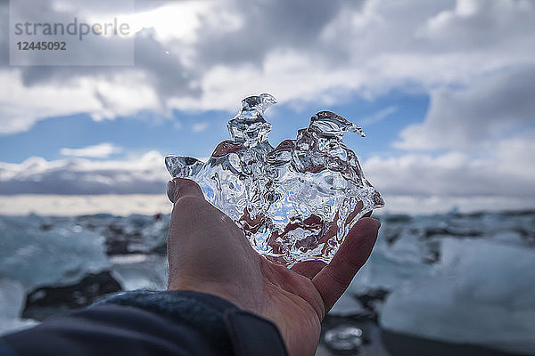 Mann hält ein Stück Eis in Jokulsarlon  Südküste  Island