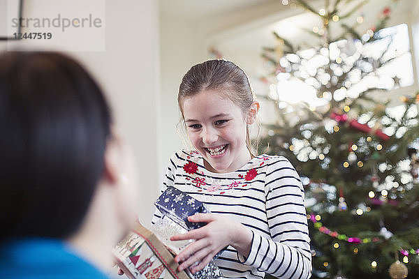 Glückliches  eifriges Mädchen beim Sammeln von Weihnachtsgeschenken