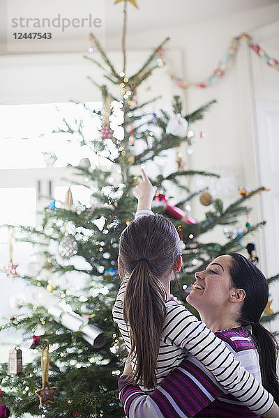 Liebevolle Mutter und Tochter mit Blick auf den Weihnachtsbaum