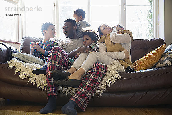 Junge Familie entspannt sich im Schlafanzug auf dem Wohnzimmersofa