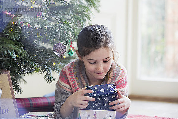 Neugieriges Mädchen hält Weihnachtsgeschenk