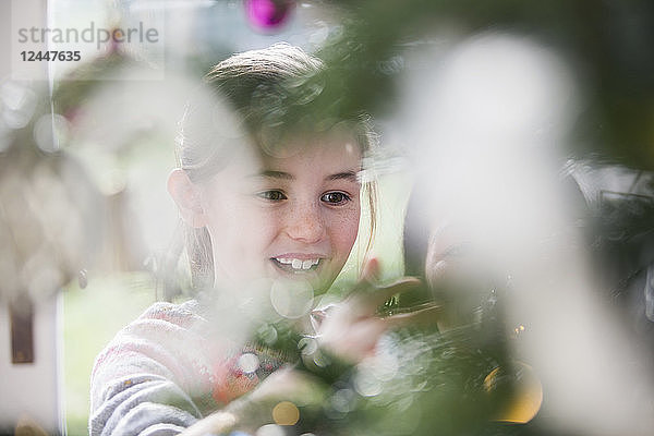 Lächelndes Mädchen beim Schmücken des Weihnachtsbaums