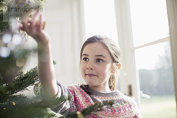 Neugieriges Mädchen berührt das Ornament am Weihnachtsbaum