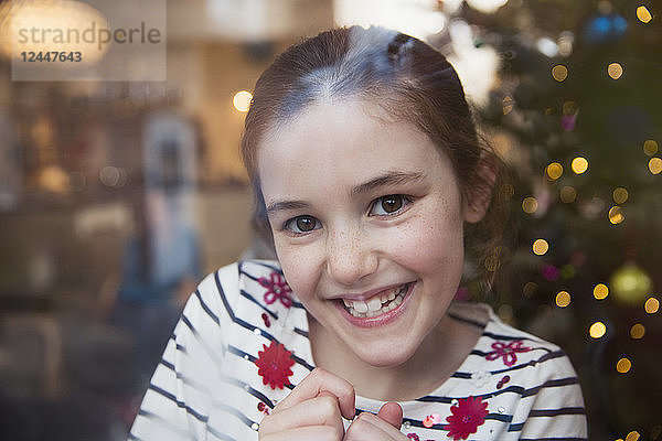 Porträt lächelndes  selbstbewusstes Mädchen im Weihnachtswohnzimmer