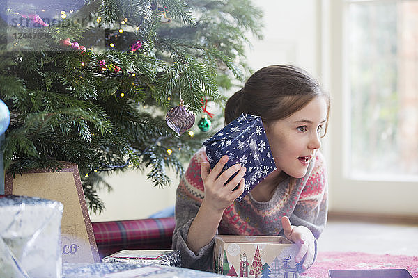 Neugieriges Mädchen schüttelt Weihnachtsgeschenk