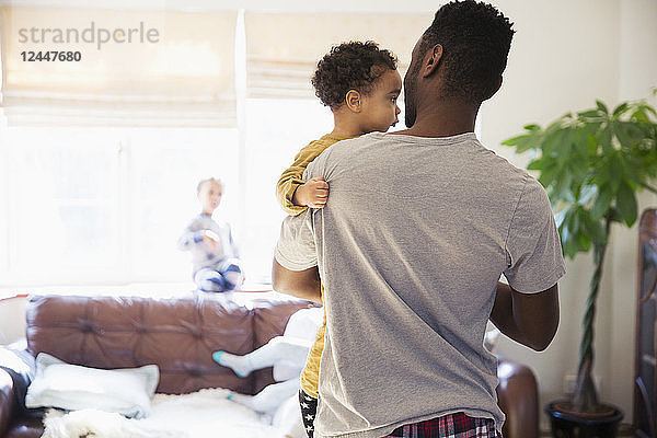 Vater hält seinen kleinen Sohn im Wohnzimmer