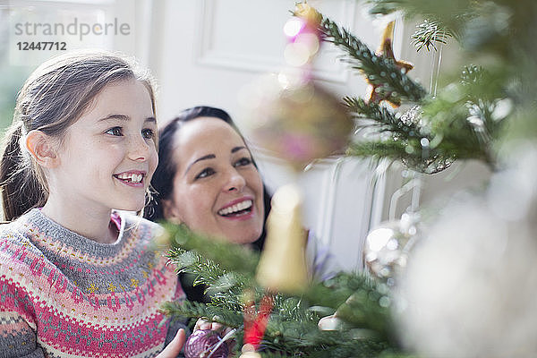 Glückliche Mutter und Tochter beim Schmücken des Weihnachtsbaums