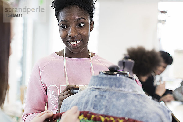 Smiling teenage girl designing denim jacket in fashion design class