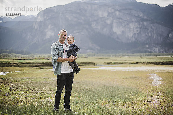 Portrait father and baby son standing in rural field